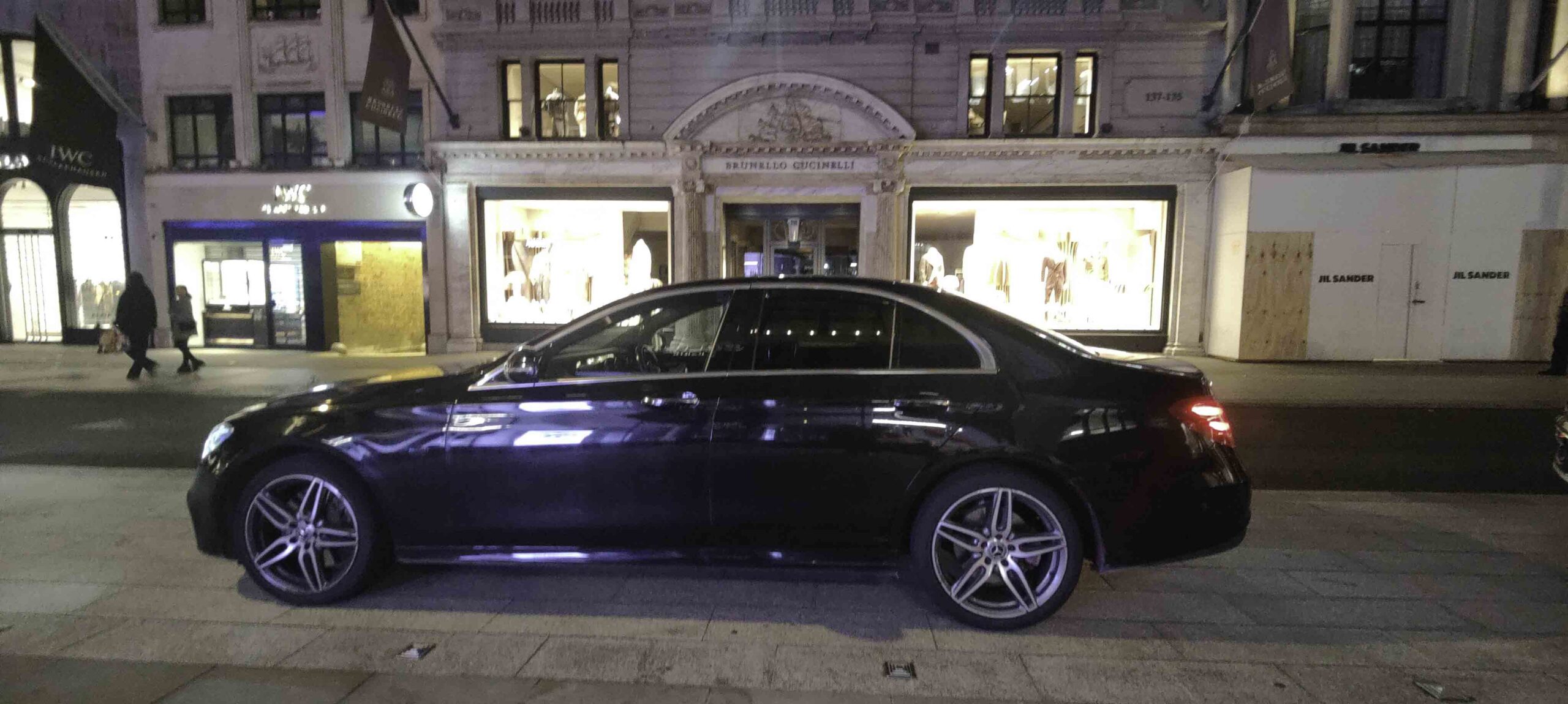 Black Mercedes E-Class parked on a London street at night